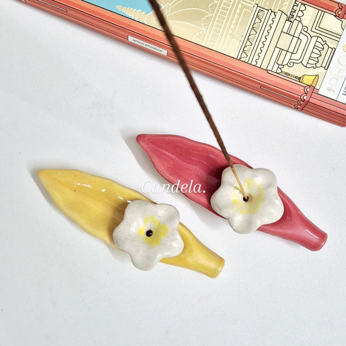 Ceramic incense stick holder with white flower design in yellow and red